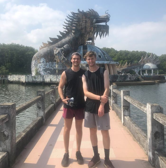 two young men in front of a dragon sculpture